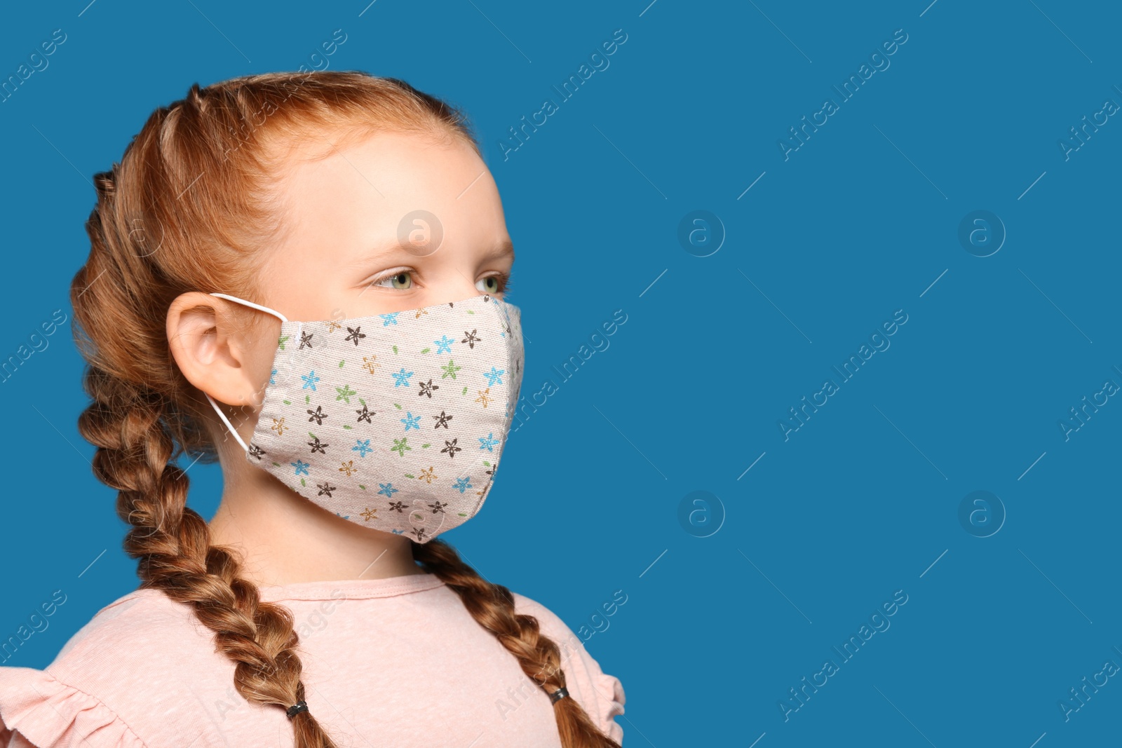 Photo of Preteen girl in protective face mask on blue background, space for text