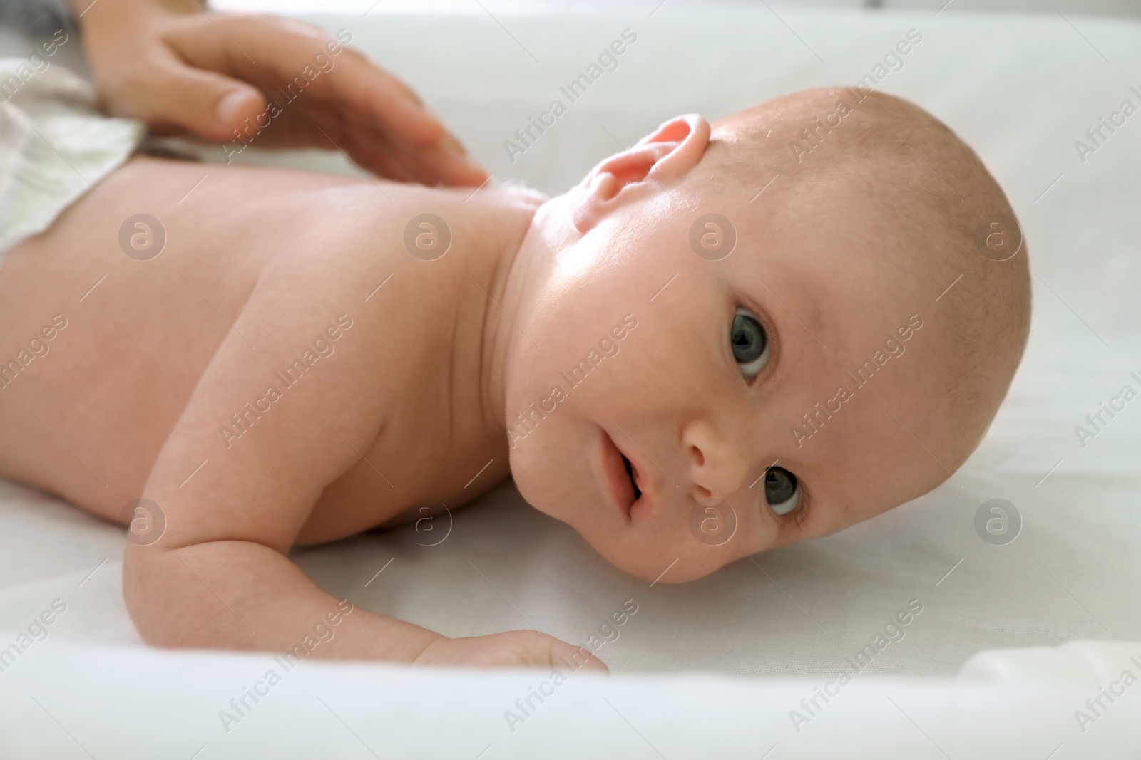 Photo of Cute little baby lying on changing table, closeup