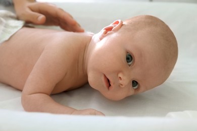 Photo of Cute little baby lying on changing table, closeup