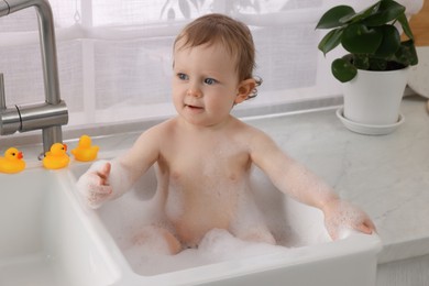 Photo of Cute little baby bathing in sink at home