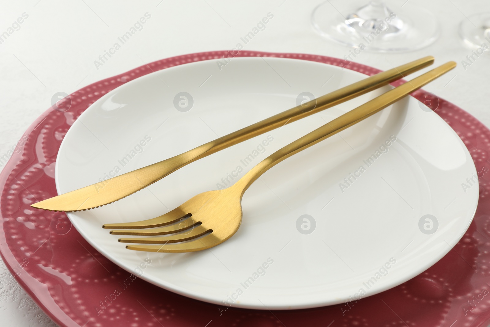 Photo of Stylish setting with cutlery and plates on white textured table, closeup