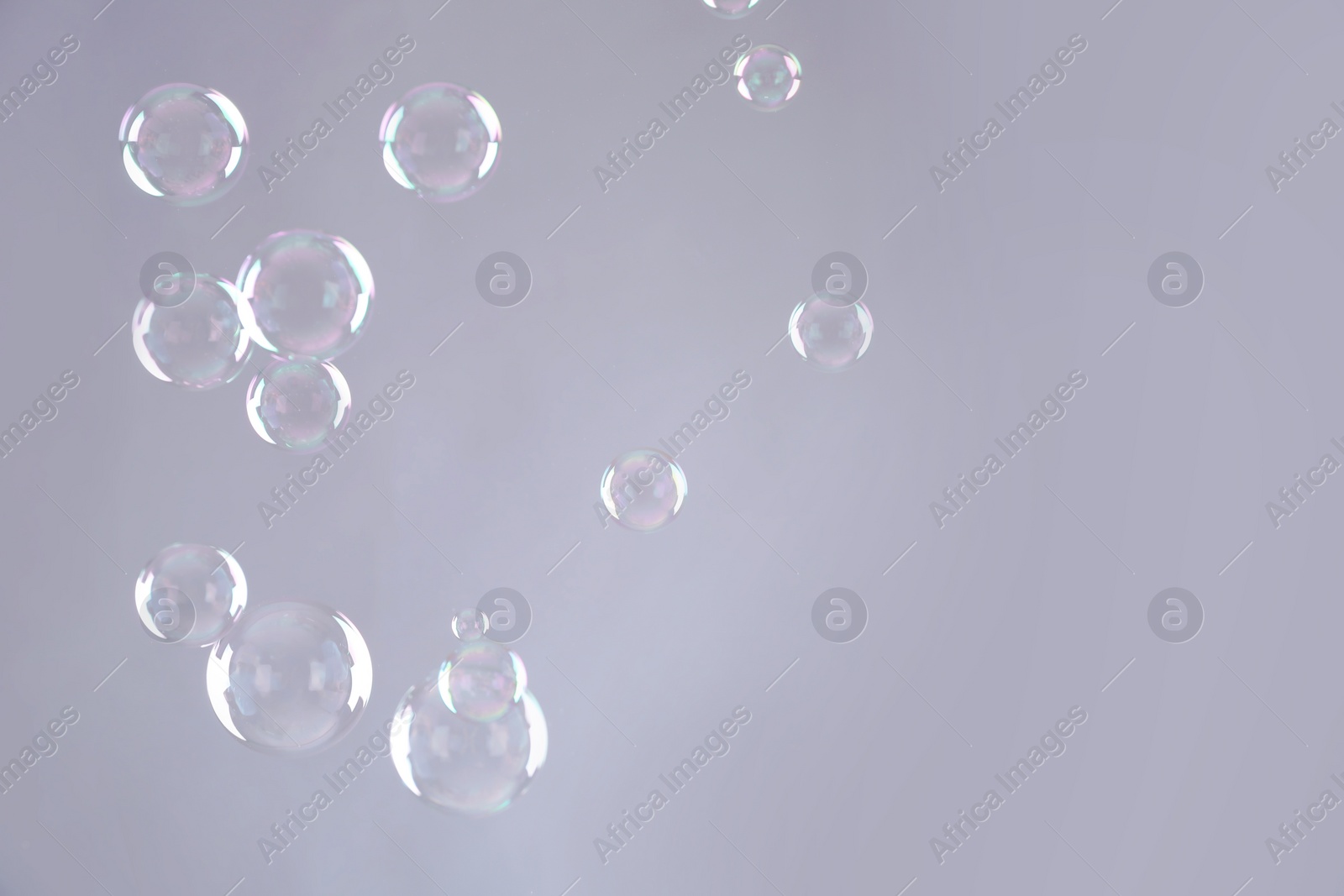 Photo of Beautiful translucent soap bubbles on grey background. Space for text