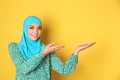 Photo of Portrait of young Muslim woman in hijab against color background. Space for text