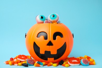 Halloween trick or treat bucket with different sweets on light blue