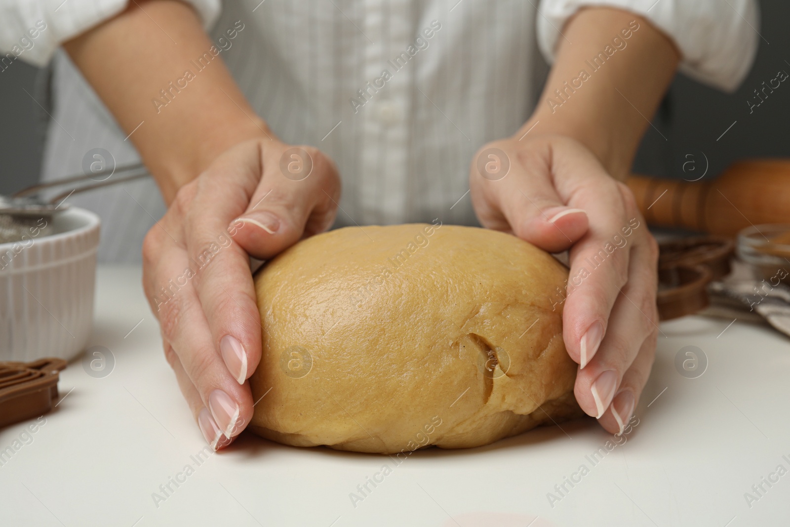 Photo of Woman kneading dough for cookies at white table, closeup