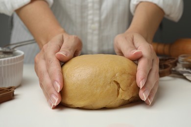 Photo of Woman kneading dough for cookies at white table, closeup