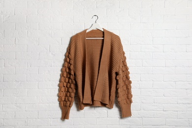 Hanger with stylish sweater on brick wall