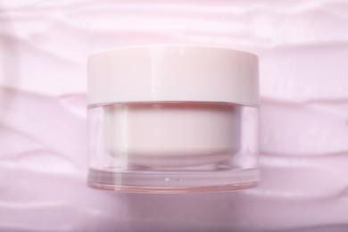 Photo of Jar with cosmetic product and smear of pink body cream, top view