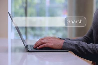 Search bar of website over laptop. Man using computer at table, closeup