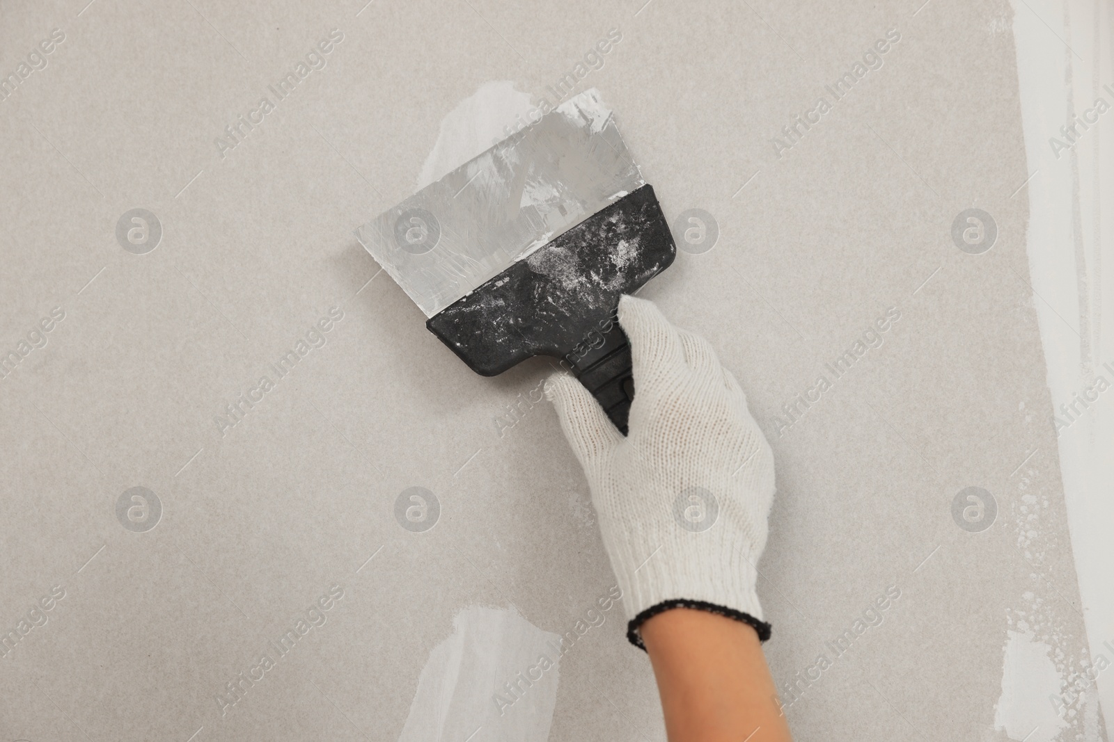 Photo of Worker plastering wall with putty knife, closeup