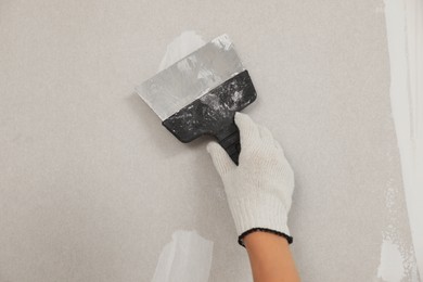 Worker plastering wall with putty knife, closeup