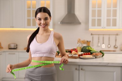 Photo of Happy woman measuring waist with tape in kitchen. Keto diet