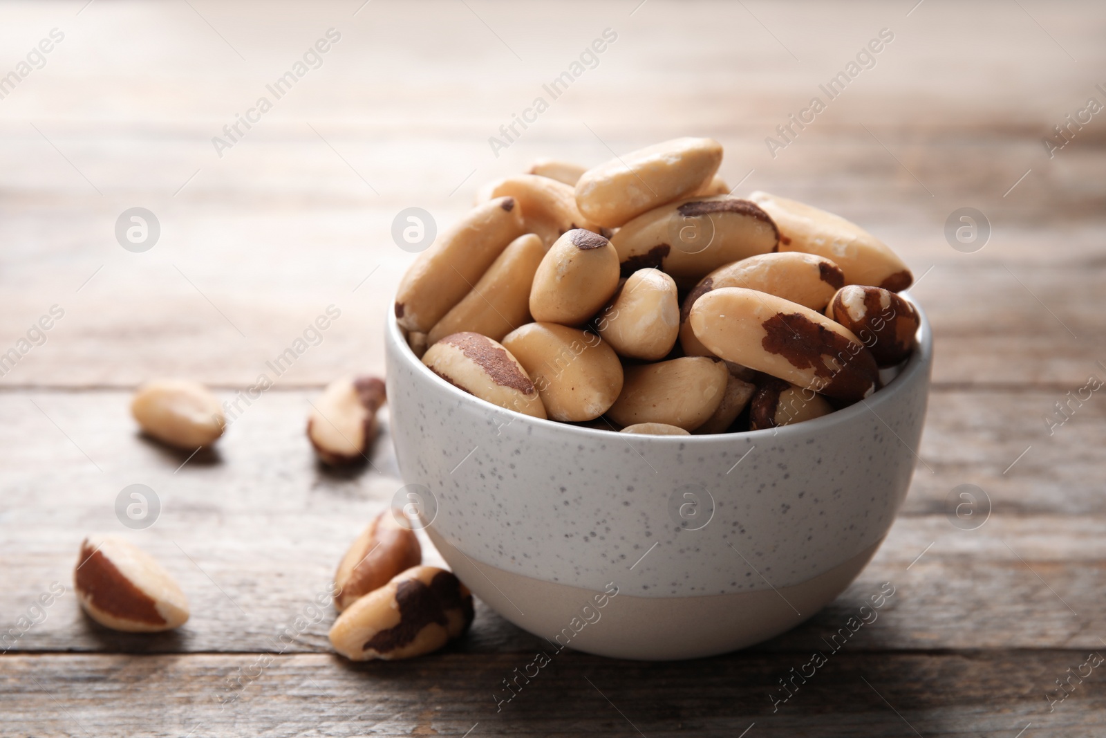 Photo of Bowl with tasty Brazil nuts on wooden table