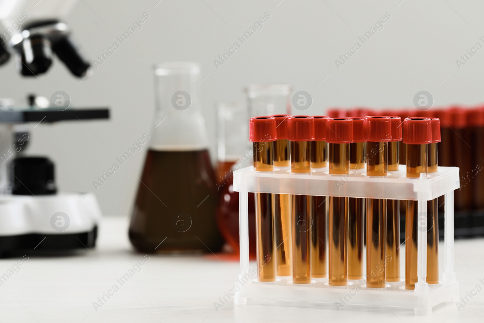 Photo of Test tubes with brown liquid on white table. Space for text