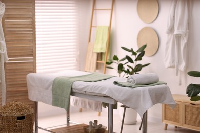 Photo of Comfortable massage table with clean towels in spa center