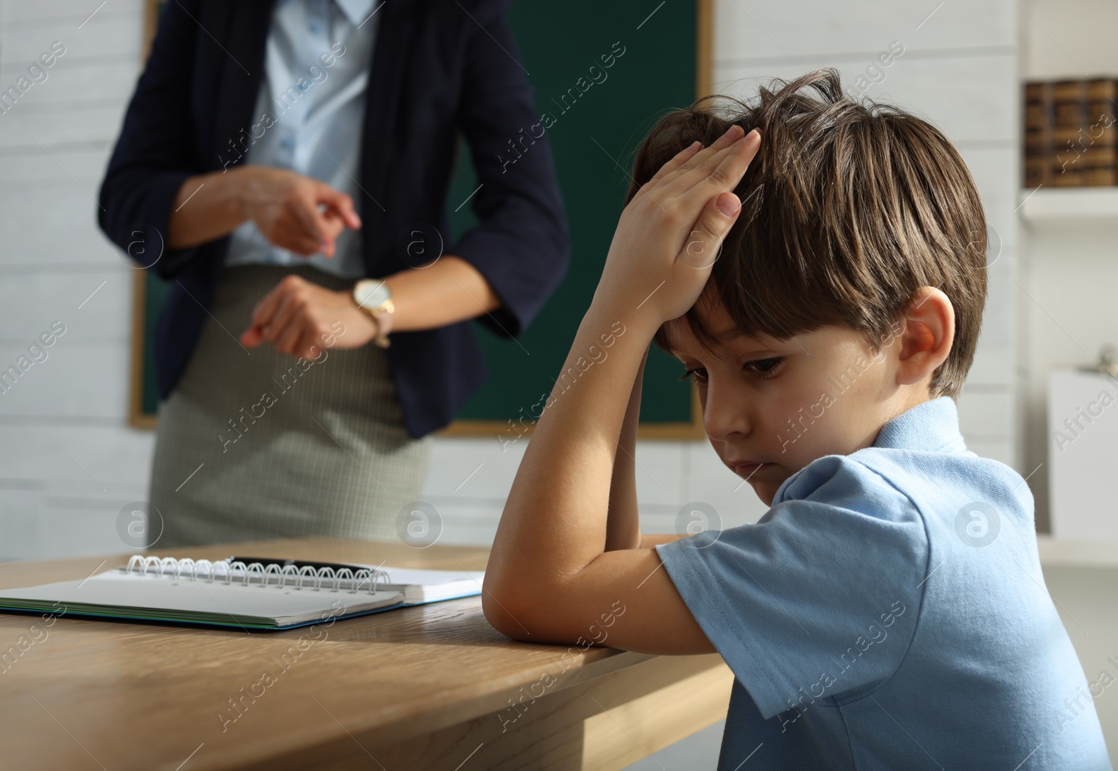 Photo of Teacher pointing on wrist watch while scolding pupil for being late in classroom