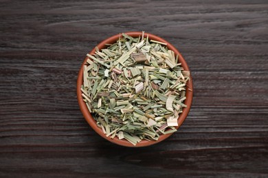 Photo of Bowl with aromatic dried lemongrass on wooden table, top view