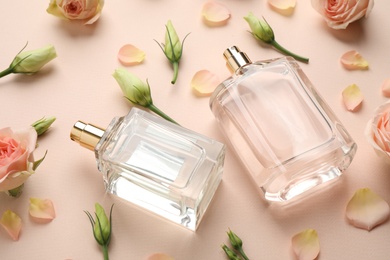 Composition with different perfume bottles and fresh flowers on beige background