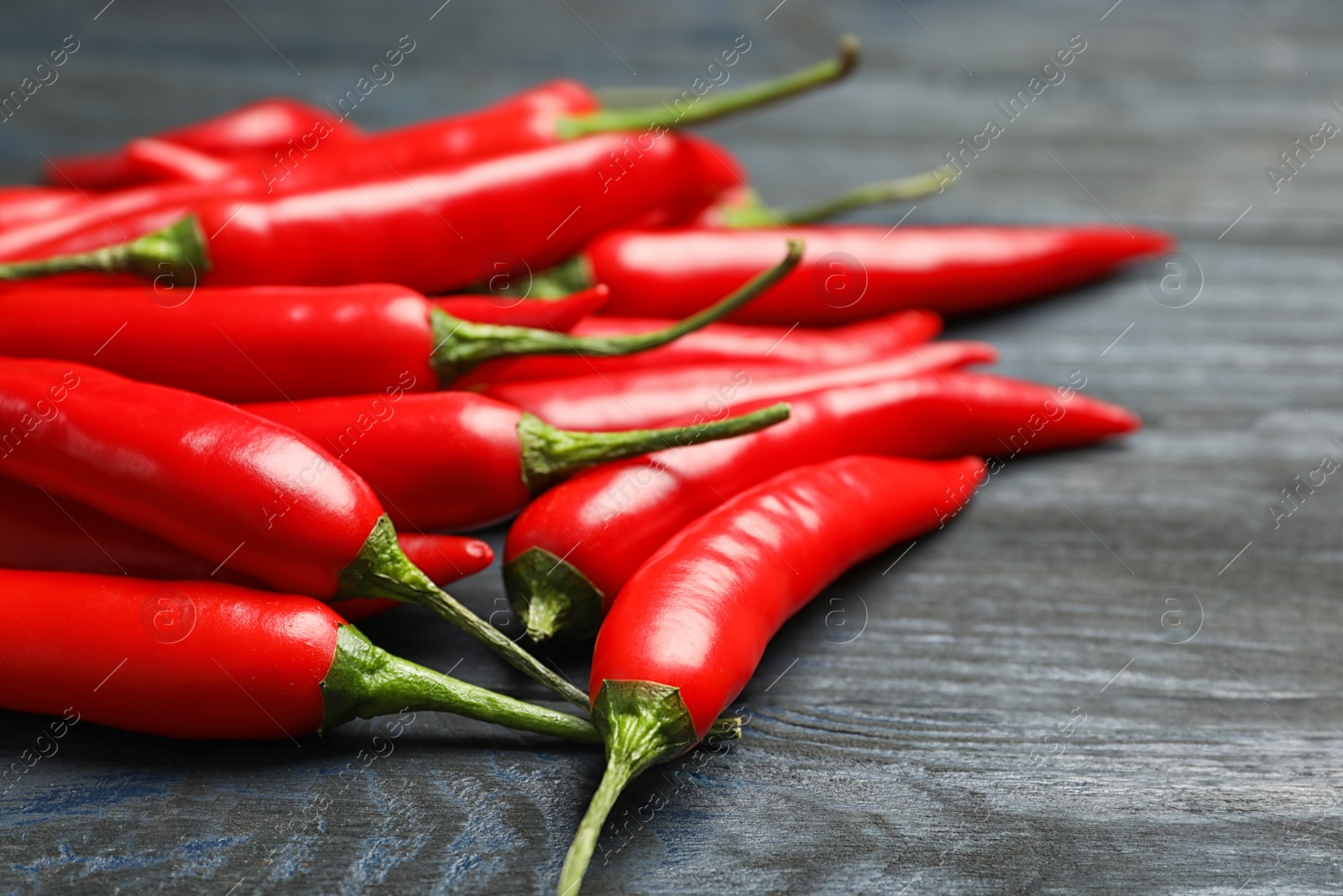 Photo of Red hot chili peppers on grey wooden table, closeup. Space for text