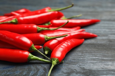 Red hot chili peppers on grey wooden table, closeup. Space for text