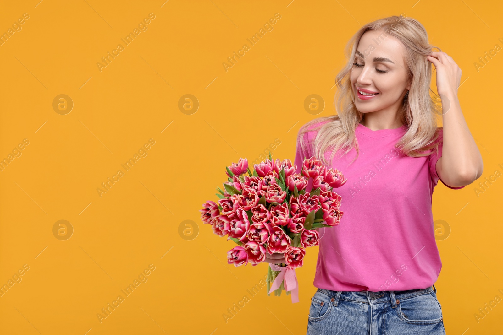 Photo of Happy young woman with beautiful bouquet on orange background. Space for text