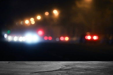 Empty black stone surface and blurred view of night city. Bokeh effect 