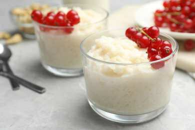 Photo of Delicious rice pudding with redcurrant on marble table, closeup