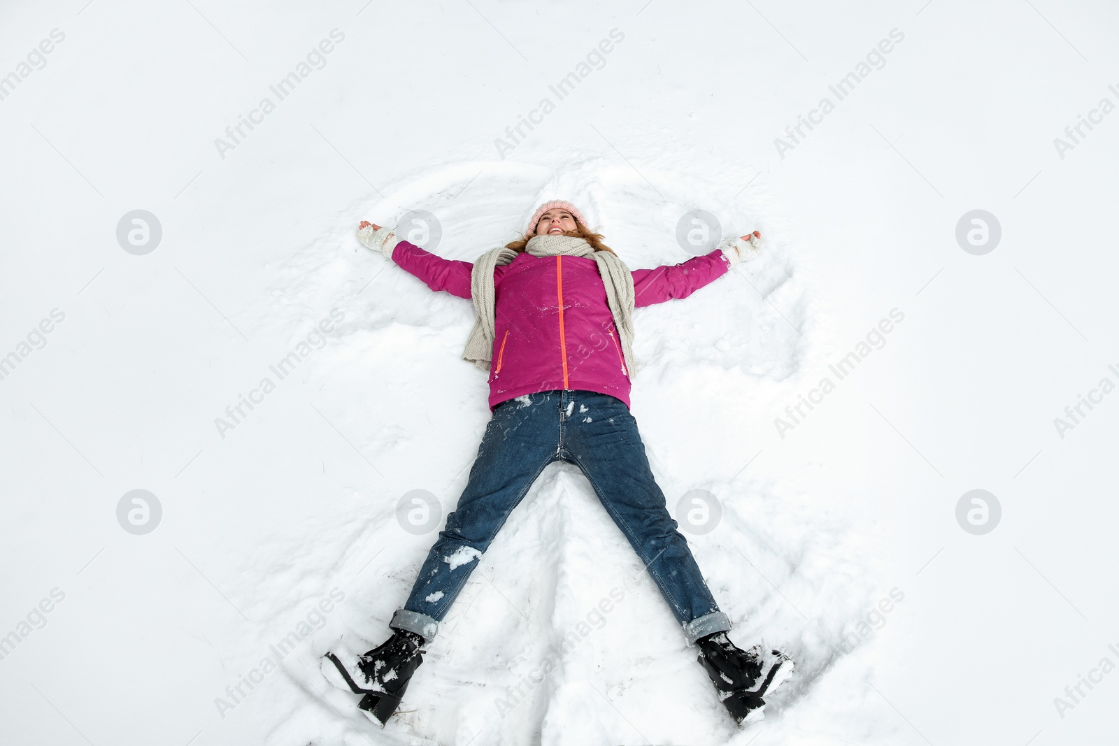 Photo of Beautiful woman making snow angel on winter day