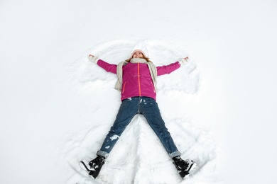 Photo of Beautiful woman making snow angel on winter day