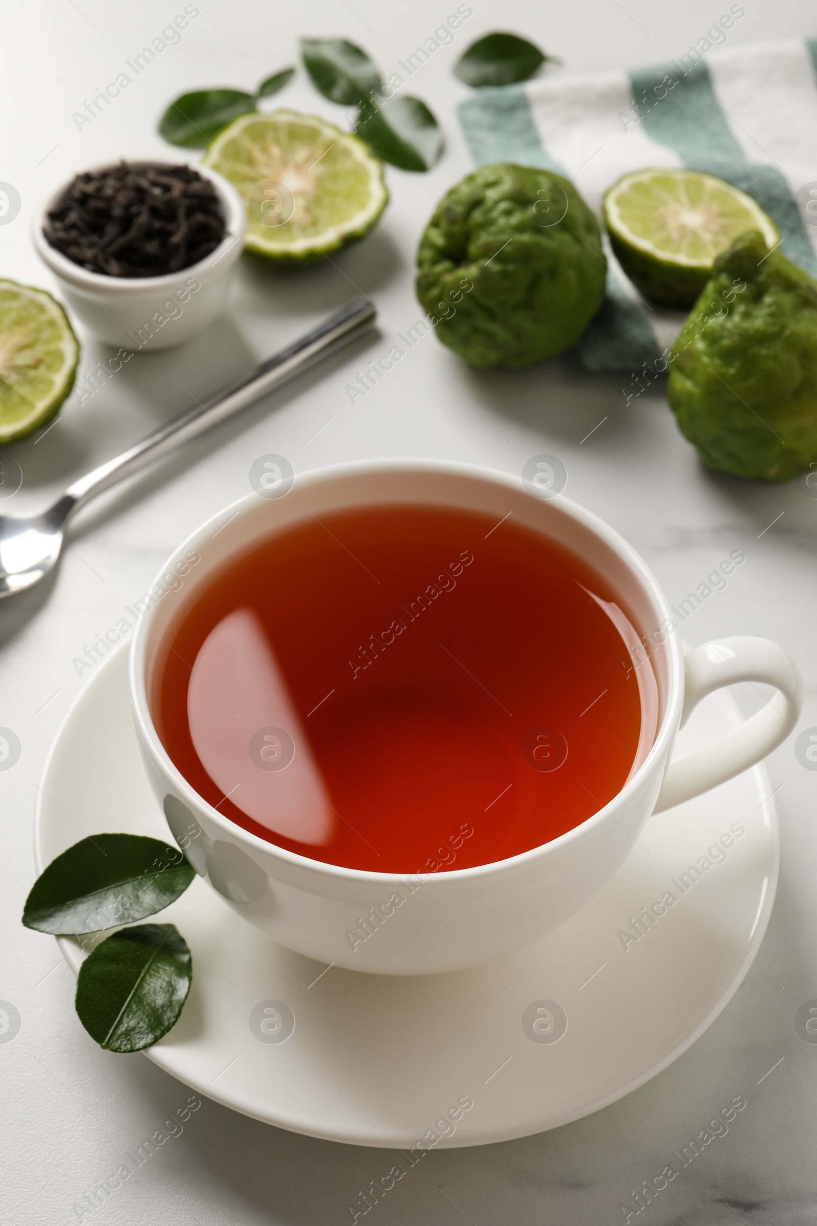 Photo of Cup of tasty bergamot tea and fresh fruits on white table