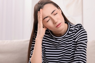 Photo of Sad woman suffering from headache at home, space for text