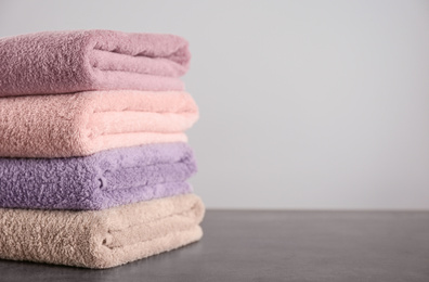 Photo of Stack of clean bath towels on dark grey table. Space for text