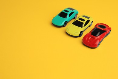 Photo of Different bright cars on yellow background, space for text. Children`s toys
