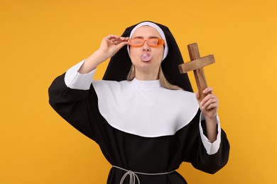 Photo of Woman in nun habit blowing bubble gum against orange background