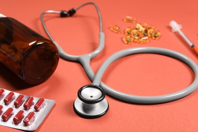 Stethoscope and pills on crimson background, closeup. Medical tool