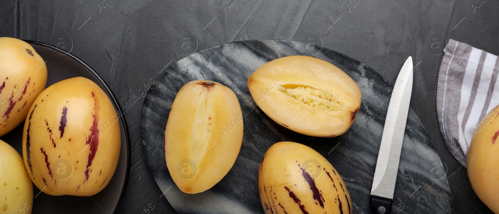 Image of Whole and cut pepino melons on dark table, flat lay. Banner design