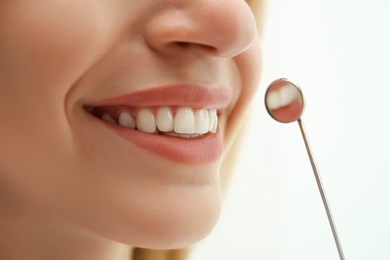 Photo of Examining patient's teeth on light background, closeup. Cosmetic dentistry