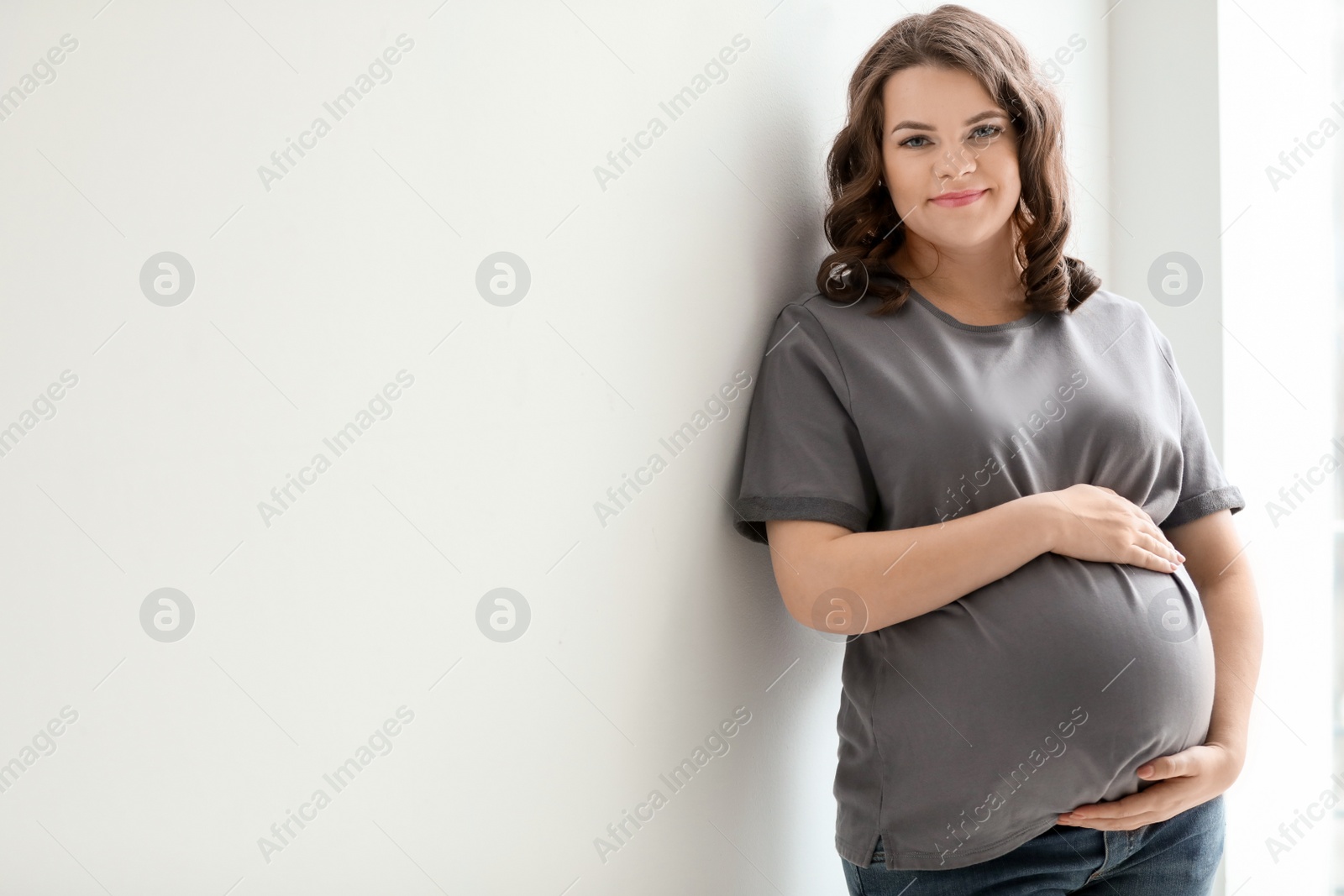 Photo of Young pregnant woman in casual clothes on light background