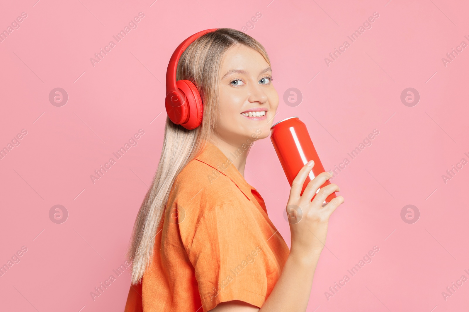 Photo of Beautiful happy woman holding red beverage can on pink background. Space for text