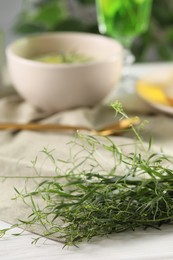 Photo of Fresh tarragon sprigs on white table. Space for text