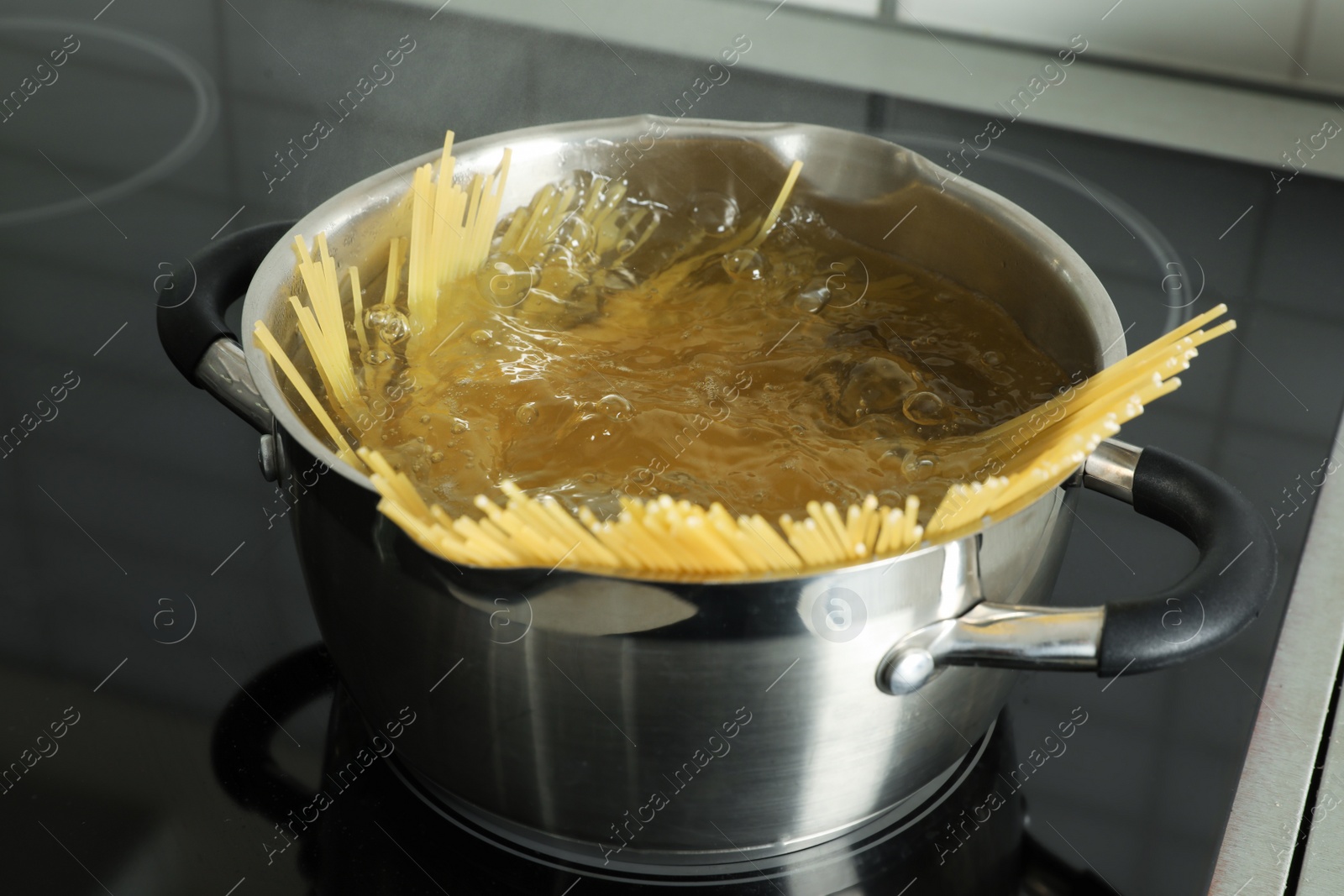 Photo of Cooking spaghetti in pot on electric stove