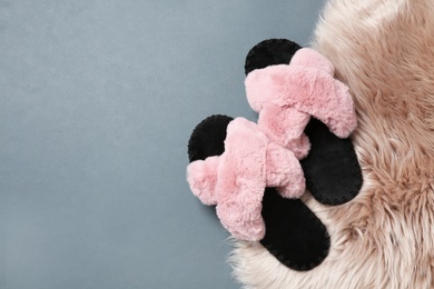 Photo of Pair of soft slippers and faux fur on floor, flat lay. Space for text