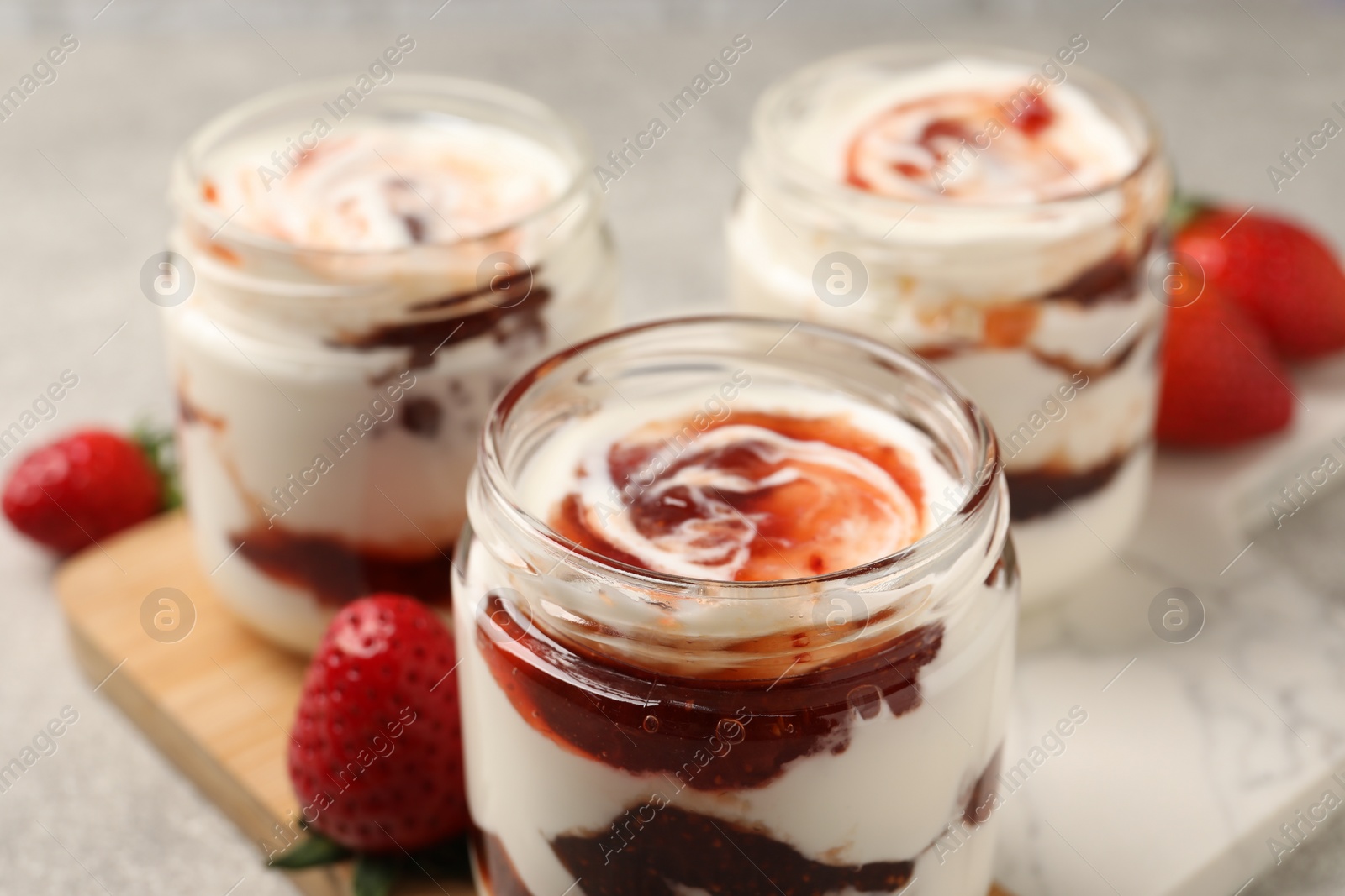 Photo of Tasty yoghurt with jam and strawberries on table, closeup