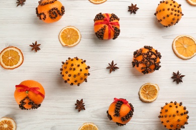 Flat lay composition with pomander balls made of fresh tangerines and cloves on white wooden table