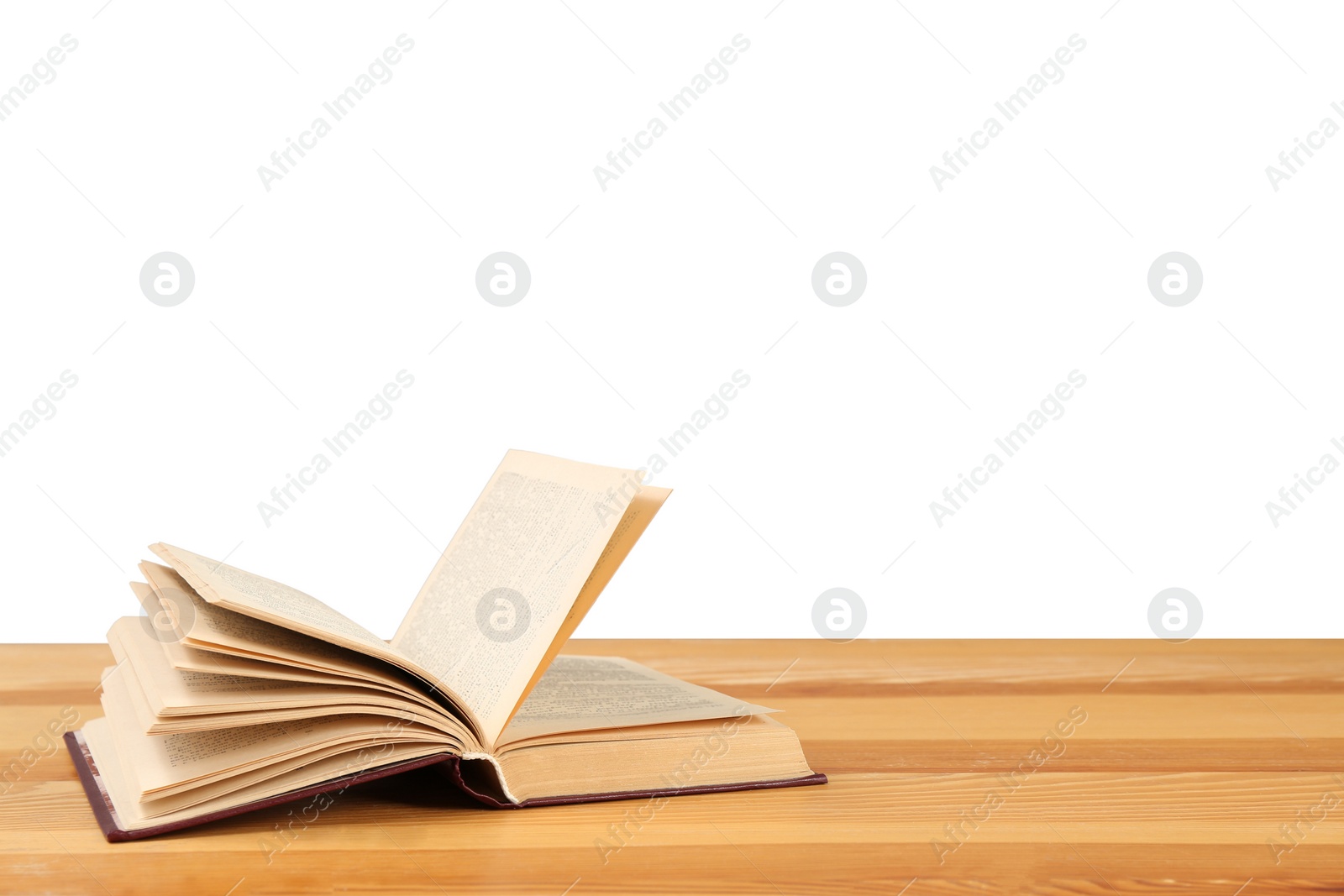 Photo of Open book on wooden table against white background. Library material