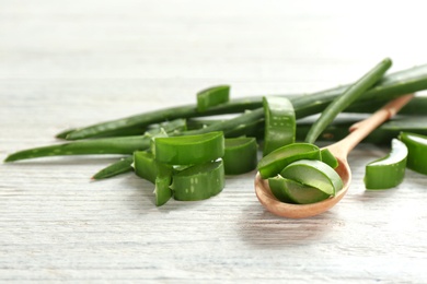 Spoon with slices of aloe vera on wooden table