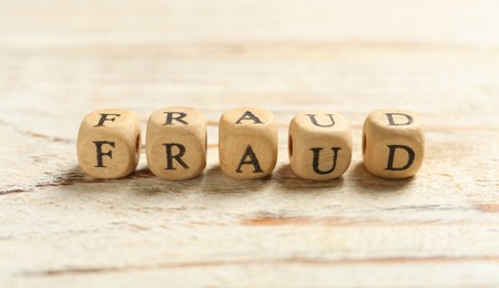 Photo of Word Fraud of cubes with letters on white wooden background