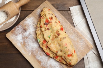 Photo of Unbaked Stollen with candied fruits and raisins on wooden table, flat lay