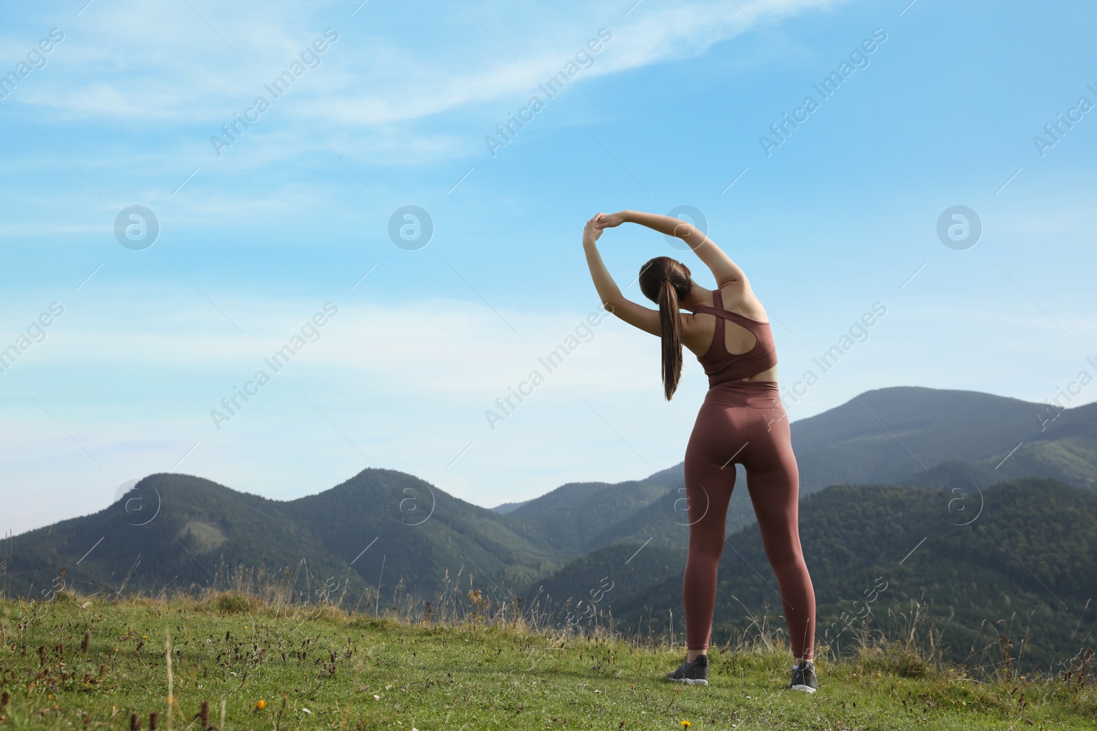 Photo of Woman doing morning exercise in mountains, back view. Space for text