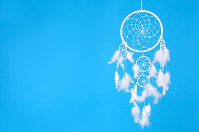 Photo of Beautiful handmade dream catcher on light blue background. Space for text